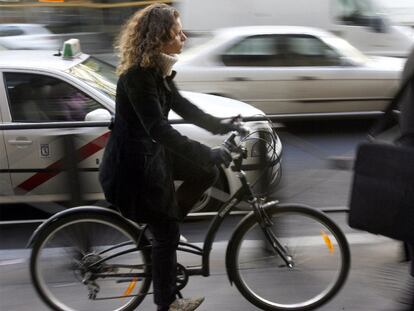 Una mujer circula en bicicleta por la acera de una calle de Madrid.