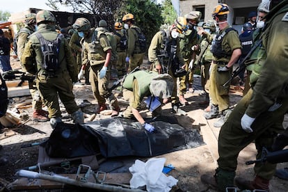 Israeli soldiers prepare to remove the body of a compatriot, killed during an attack by the Palestinian militants, in Kfar Aza, south of Israel bordering Gaza Strip, on October 10, 2023. 