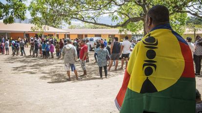 Homem com a bandeira da Nova Caledônia aguarda para votar.