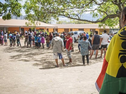 Un home amb una bandera de Nova Caledònia davant d'un col·legi electoral durant el vot sobre la independència