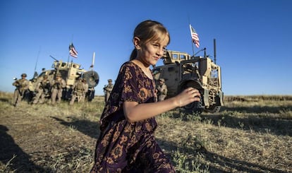 Una niña corre por un campo cerca de varios vehículos militares en la ciudad siria de al-Malikiyah, cerca de la frontera turca, el 7 de junio de 2020.