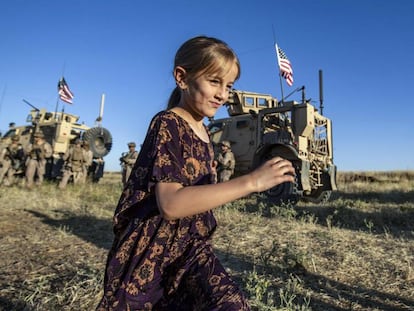 Una niña corre por un campo cerca de varios vehículos militares en la ciudad siria de al-Malikiyah, cerca de la frontera turca, el 7 de junio de 2020.