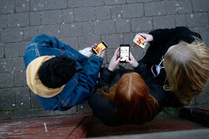 Three teenagers using their cell phones.