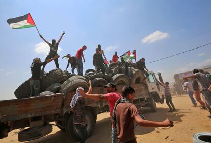 Varios manifestantes se suben a un camión repleto de neumáticos para ser quemados en las protestas cerca de la frontera israelí, al este de Khan Yunis, en la Franja de Gaza. 