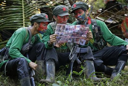 In this photo taken Nov. 23, 2016, members of the New People's Army communist rebels with face painted to conceal their identities, reads a local paper at their guerrilla encampment tucked in the harsh wilderness of the Sierra Madre mountains southeast of Manila, Philippines. Communist guerrillas warn that a peace deal with President Rodrigo Duterte's government is unlikely if he won't end the Philippines' treaty alliance with the United States and resist control by other countries. (AP Photo/Aaron Favila)