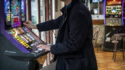 Un hombre echa una moneda a una máquina tragaperras en un bar de Valencia.