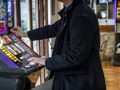 Un hombre echa una moneda a una máquina tragaperras en un bar de Valencia.