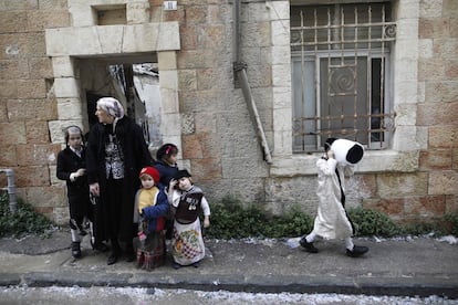 Una familia judía ultraortodoxa aguarda de pie disfrazada para celebrar la fiesta de Purim, en el barrio de Mea Shearim.