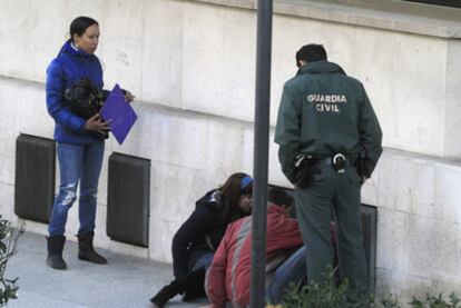 Un guardia civil observa cómo unos familiares hablan con los detenidos desde la calle.