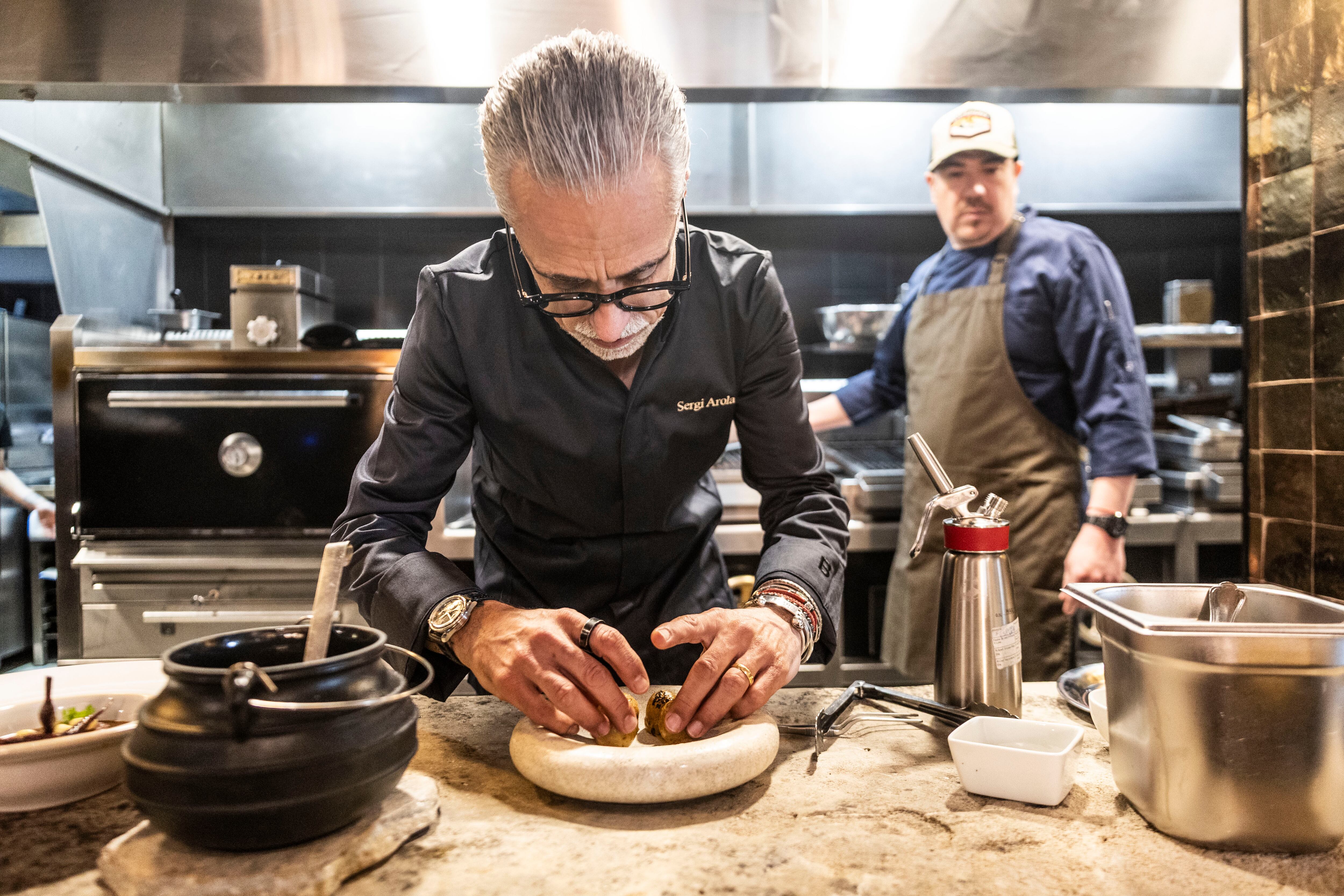 Sergi Arola, el pasado viernes, emplatando una receta en la cocina de Austral, en Madrid. Al fondo, Felipe Farías, jefe de cocina del grupo de restauaración chileno Los Lirios, propietario del establecimiento.