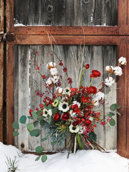 Un ramo de invierno hecho con algodón, ranúnculo y anémonas adorna la ventana de madera de un almacén abandonado.