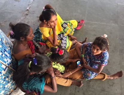 Un grupo de niñas se juntan al rededor de un teléfono en una estación de trenes de Bombay.