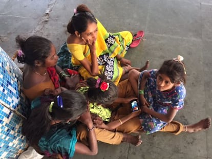 Un grupo de niñas se juntan al rededor de un teléfono en una estación de trenes de Bombay.