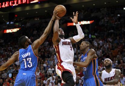 Dwayne Wade intenta encestar entre Kevin Durant y James Harden