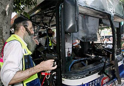 Un judío ultraortodoxo porta una bolsa con restos humanos junto al autobús objeto del ataque terrorista.