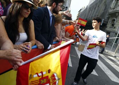 Un voluntario reparte banderas de España entre el público que se ha acercado al Congreso.