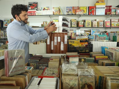 Un hombre coloca varios libros en una de las casetas de la 44ª edición de la Feria del Libro Antiguo, en el Paseo de Recoletos, a 5 de mayo de 2022, en Madrid.