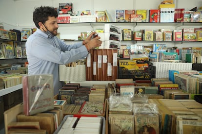 Un hombre coloca varios libros en una de las casetas de la 44ª edición de la Feria del Libro Antiguo, en el Paseo de Recoletos, a 5 de mayo de 2022, en Madrid.