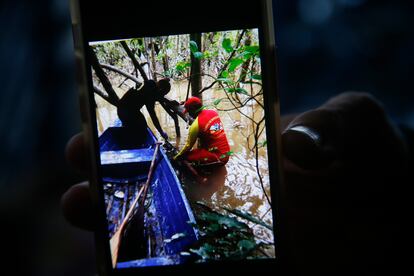 Un bombero sostiene un teléfono celular con una imagen que muestra el momento en que se encontró una mochila durante la búsqueda del indigenista y el periodista.