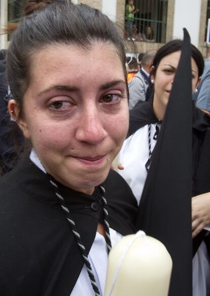 Una nazarena de la hermandad de Santa Genoveva llora de alegría al saber que su cofradía iba a procesionar después de retrasarse más de una hora ante la posibilidad de lluvia.