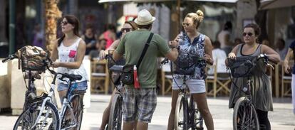 Cuatro turistas en bicicleta escuchan las indicaciones de su gu&iacute;a en el centro hist&oacute;rico de Valencia. EFE/Archivo