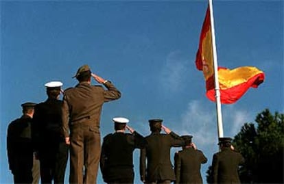 Un grupo de oficiales de complemento saluda a la bandera española izada en la madrileña plaza de Colón.