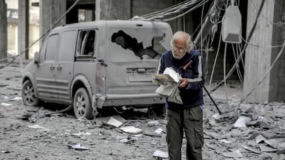 Un palestino lee un libro junto a un automóvil destruido por un bombardeo israelí en la ciudad de Gaza, el 3 de marzo de 2024.