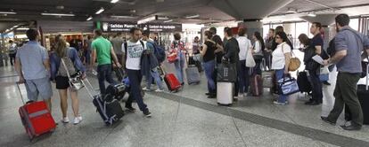 Varios viajeros esperan en la estaci&oacute;n de tren de Atocha, en Madrid. 