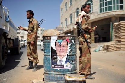 Varios soldados realizan un control a los veh&iacute;culos junto a un cartel electoral del &uacute;nico aspirante a las elecciones y vicepresidente yemen&iacute;, Abdo Rabo Mansur Hadi, en Sana, Yemen.