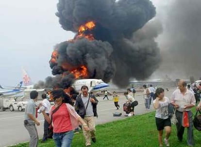 Los pasajeros se alejan del avión taiwanés incendiado ayer en el aeropuerto japonés de Naha.