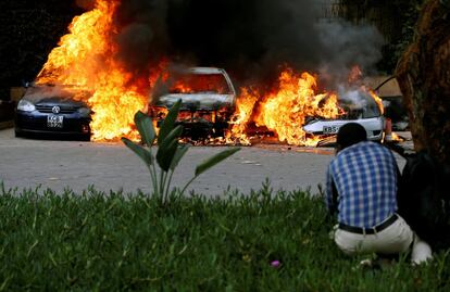 Un hombre se protege tras la explosión de varios coches junto al hotel.