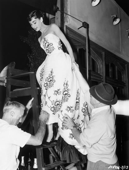 Dos hombres ayudan a Audrey Hepburn a acomodar el icnico vestido durante el rodaje de la pelcula 'Sabrina', en 1950.