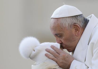 El papa Francisco besa a un niño a su llegada a la audiencia general en el Vaticano.