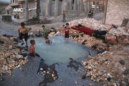 Foto proporcionada por el grupo Alepo Media Center y realizada el 31 de agosto de 2016 donde se muestra a unos ni?os sirios ba?ndose en un agujero lleno de agua provocado por el ataque de misiles en la zona de Sheikh Saeed en la provincia de Alepo (Siria).