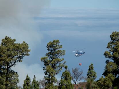Uno de los helicópteros que participan este domingo en las labores de extinción del incendio forestal de La Palma realiza una maniobra de aproximación para apagar un foco reavivado por el viento en el cortafuego de la localidad de Las Palomas, en el municipio de Garafía.