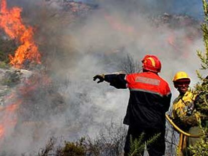 Dos bomberos luchan contra las llamas en el incendio forestal de Benissa.