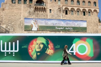 Una mujer pasa ante un cartel que conmemora el derrocamiento de la monarquía, en Trípoli en 2009.