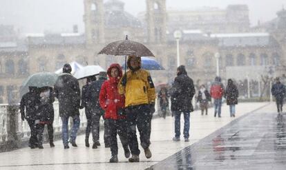 Paseantes bajo la nieve en el centro de San Sebastián.