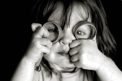 Niña juega con unas lupas.