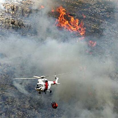 Un helicóptearo, en el momento de descargar agua sobre el incendio, ayer en Argelita.