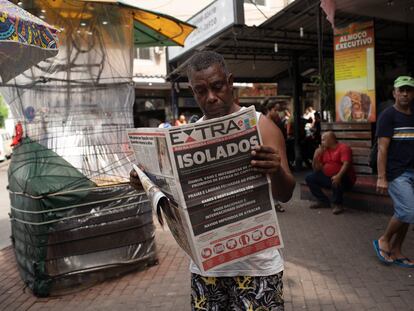 Un hombre lee un periódico con el titular en portugués "Aislado. Río en guerra contra el coronavirus" en Río de Janeiro, Brasil, el 20 de marzo de 2020.