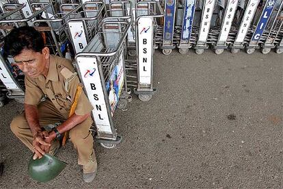 Un policía descansa en un carrito para las maletas en el aeropuerto, vacío por la huelga, de Kolkata (Calcuta).