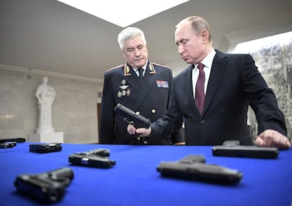 El presidente ruso Vladimir Putin sostiene una pistola durante una exposición junto al ministro del Interior ruso Vladimir Kolokoltsev, antes de la reunión anual de la Junta del Ministerio del Interior en Moscú.
