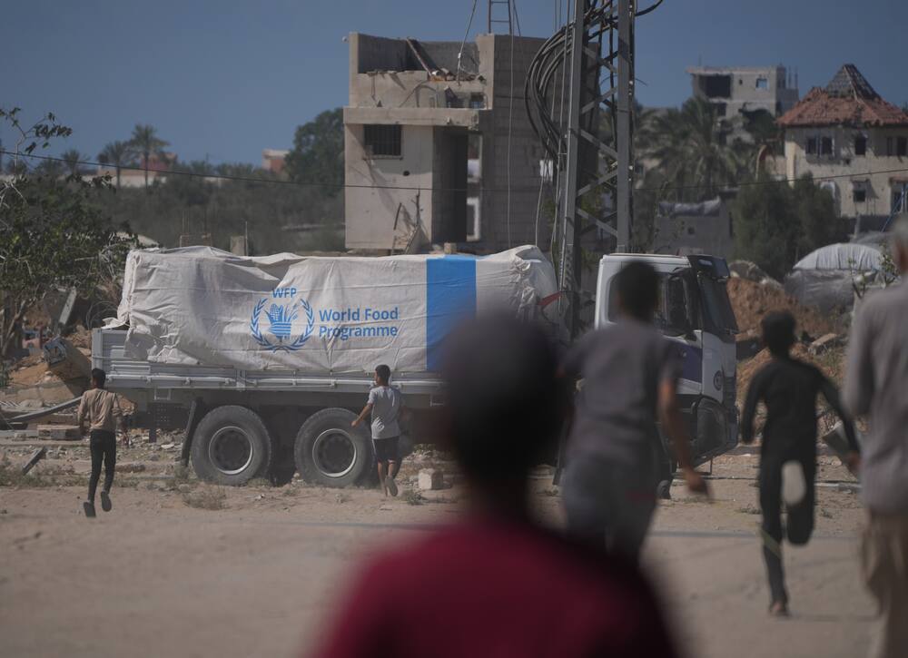 Des Palestiniens se précipitent mercredi vers des camions transportant l'aide du Programme alimentaire mondial alors qu'ils traversent Deir Al Balah, dans le centre de Gaza.
