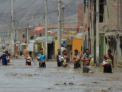 No norte de Lima, moradores caminham na água barrenta.