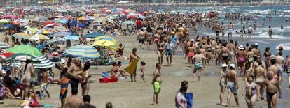 Veraneantes disfrutan al pie de los apartamentos de la playa de Cullera, en Valencia.