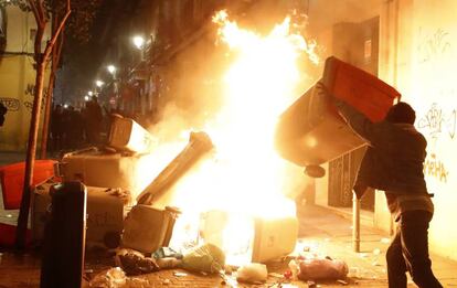 A man sets a trash bin on fire in Calle Mesón de Paredes.