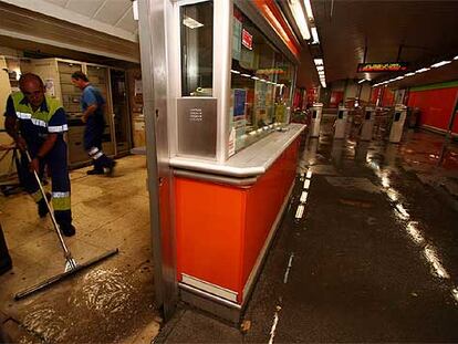 Un operario del metro limpia de agua la taquilla de la estación de Marqués de Vadillo.