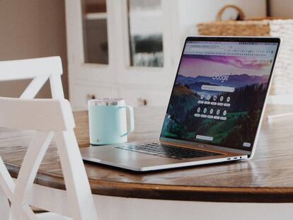 MacBook en una mesa al lado de una taza