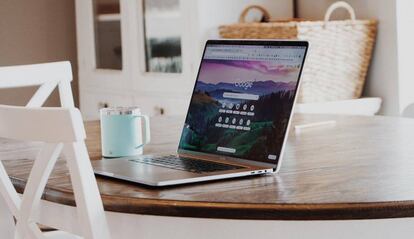 MacBook en una mesa al lado de una taza